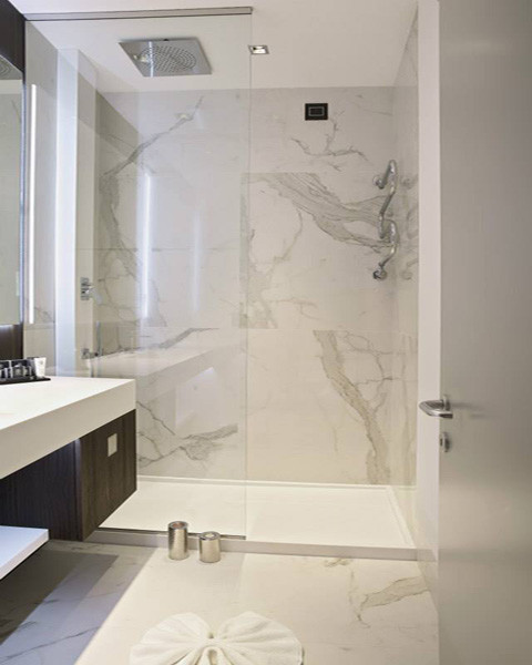 Inredning av ett klassiskt badrum, med öppna hyllor, vita skåp, marmorbänkskiva, en öppen dusch, vita väggar och marmorgolv