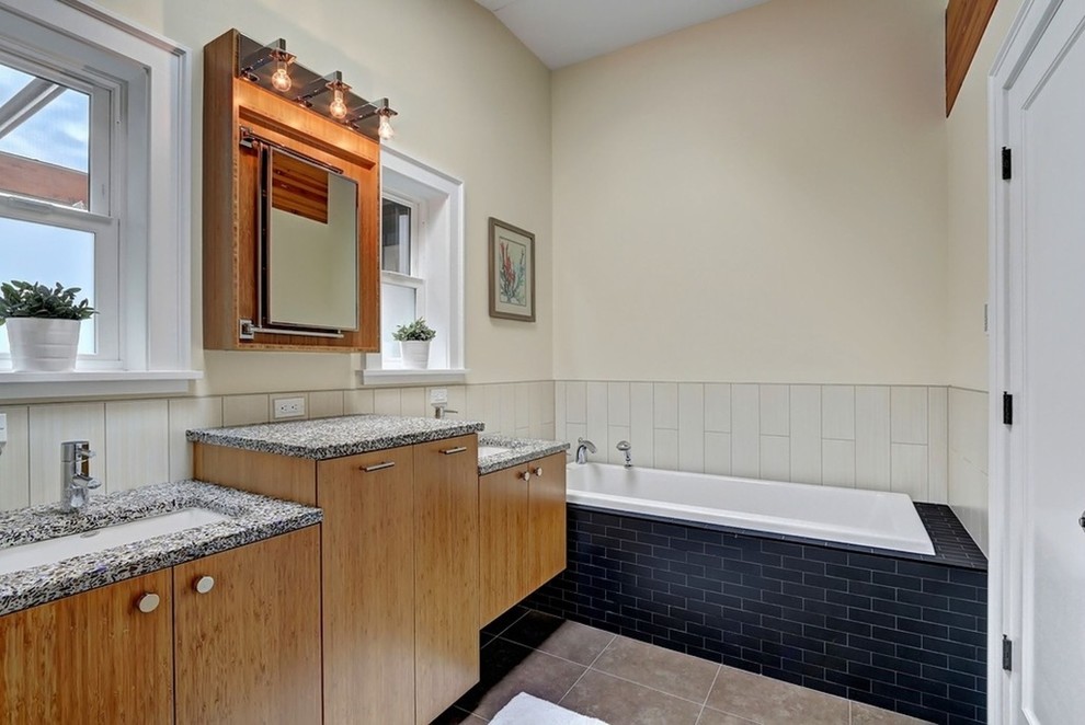 Inredning av ett modernt badrum, med ett nedsänkt handfat, släta luckor, skåp i mörkt trä, bänkskiva i terrazo, ett platsbyggt badkar, porslinskakel och klinkergolv i porslin