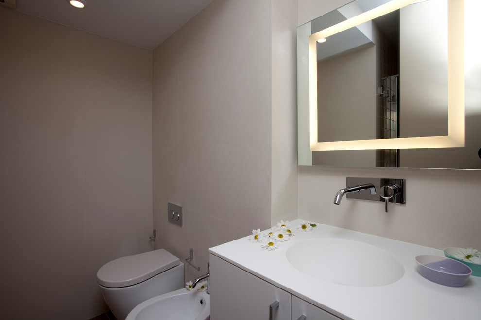 Exempel på ett mellanstort modernt badrum för barn, med vita skåp, en dusch i en alkov, en vägghängd toalettstol, beige kakel, porslinskakel, beige väggar, klinkergolv i porslin, ett integrerad handfat, bänkskiva i kvarts och släta luckor