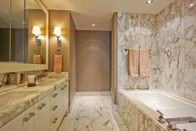 Cette image montre une salle de bain principale design de taille moyenne avec un lavabo encastré, un placard à porte plane, des portes de placard blanches, un plan de toilette en marbre, une baignoire encastrée, un carrelage multicolore, des dalles de pierre, un mur marron et un sol en marbre.