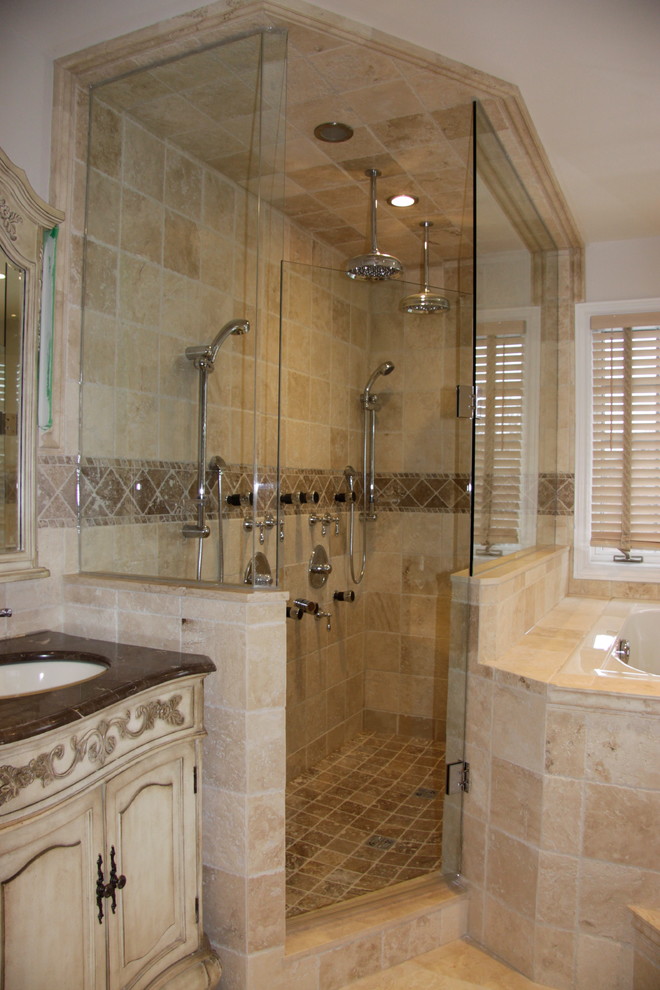 Стильный дизайн: большая главная ванная комната в классическом стиле с фасадами островного типа, светлыми деревянными фасадами, гидромассажной ванной, угловым душем, унитазом-моноблоком, бежевой плиткой, каменной плиткой, бежевыми стенами, полом из травертина, врезной раковиной и мраморной столешницей - последний тренд