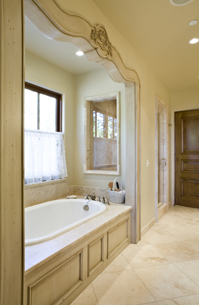 Modelo de cuarto de baño tradicional con bañera encastrada, baldosas y/o azulejos beige y ventanas