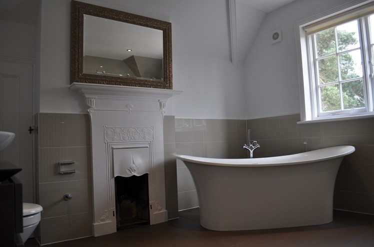 Klassisk inredning av ett badrum, med ett konsol handfat, ett fristående badkar, en vägghängd toalettstol och klinkergolv i porslin