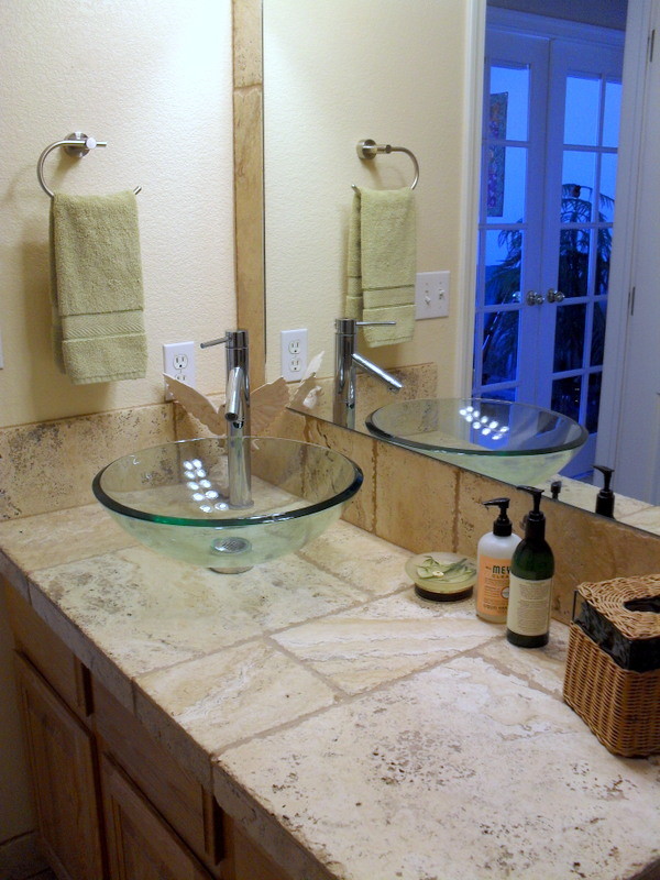 Idée de décoration pour une salle d'eau méditerranéenne avec une vasque, un plan de toilette en carrelage, un carrelage beige, un carrelage de pierre et un mur beige.