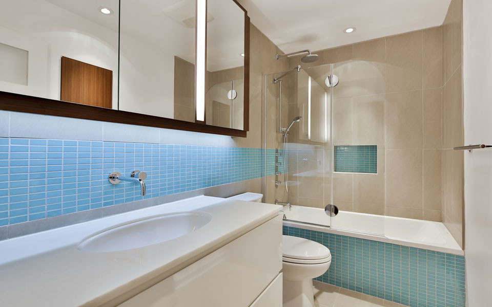 Immagine di una piccola stanza da bagno minimal con lavabo sottopiano, ante lisce, ante bianche, vasca ad alcova, vasca/doccia, WC a due pezzi, piastrelle blu, piastrelle a mosaico e pareti beige