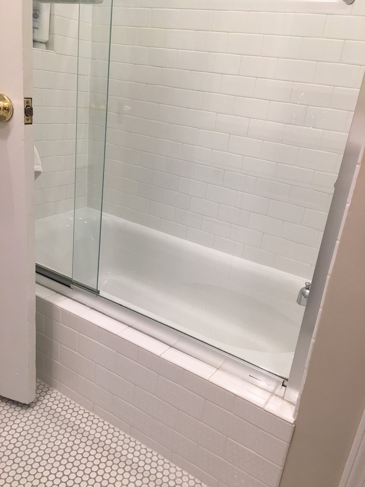 Cette photo montre une salle d'eau chic avec un placard à porte shaker, des portes de placard grises, une baignoire en alcôve, un combiné douche/baignoire, WC séparés, un carrelage blanc, un carrelage métro, un mur beige, un sol en carrelage de terre cuite, un lavabo encastré, un plan de toilette en marbre, un sol blanc et une cabine de douche à porte coulissante.