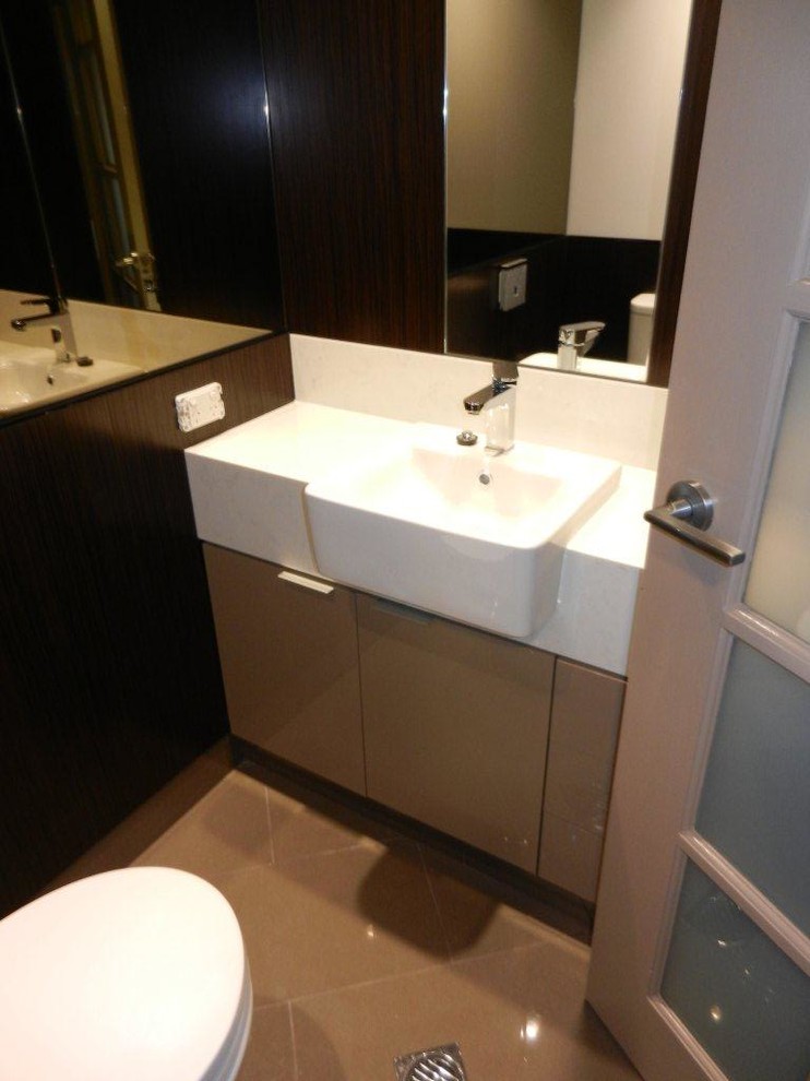 Exempel på ett litet modernt en-suite badrum, med ett nedsänkt handfat, luckor med profilerade fronter, skåp i ljust trä, laminatbänkskiva, en toalettstol med hel cisternkåpa, beige kakel, porslinskakel, bruna väggar och klinkergolv i porslin