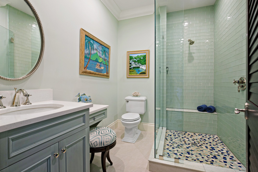 Inspiration for a tropical green tile and glass tile beige floor and single-sink bathroom remodel in Miami with recessed-panel cabinets, blue cabinets, a two-piece toilet, gray walls, an undermount sink, white countertops and a built-in vanity