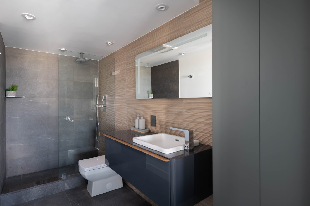Bathroom - mid-sized contemporary master gray tile and porcelain tile porcelain tile and gray floor bathroom idea in Vancouver with beaded inset cabinets, a one-piece toilet, gray walls, glass countertops, black countertops, gray cabinets and a drop-in sink