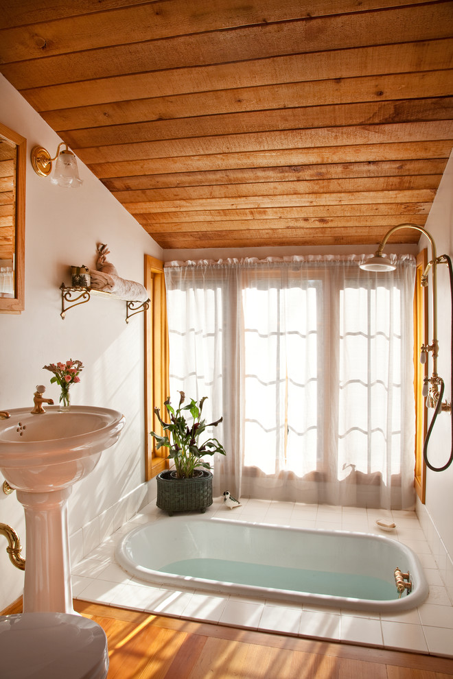Foto di una piccola stanza da bagno padronale classica con vasca ad alcova, vasca/doccia, pareti bianche, pavimento in legno massello medio, lavabo a colonna, pavimento marrone e doccia aperta