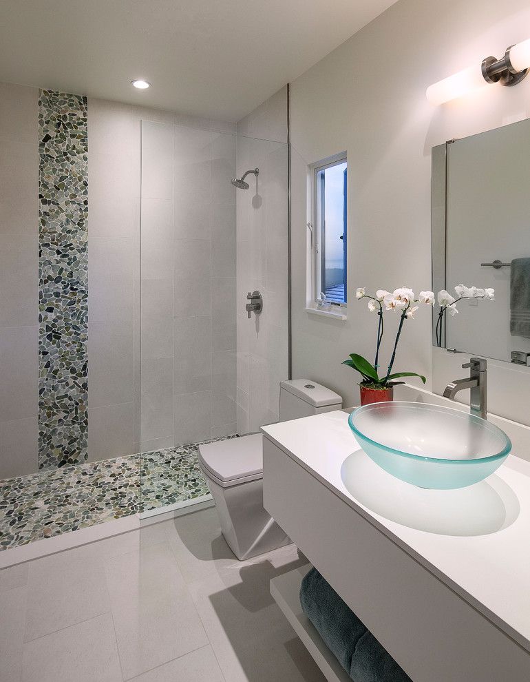 Modern inredning av ett mellanstort en-suite badrum, med vita skåp, en dusch i en alkov, en toalettstol med hel cisternkåpa, grå kakel, kakel i småsten, vita väggar, ett fristående handfat, bänkskiva i kvarts, grått golv och med dusch som är öppen