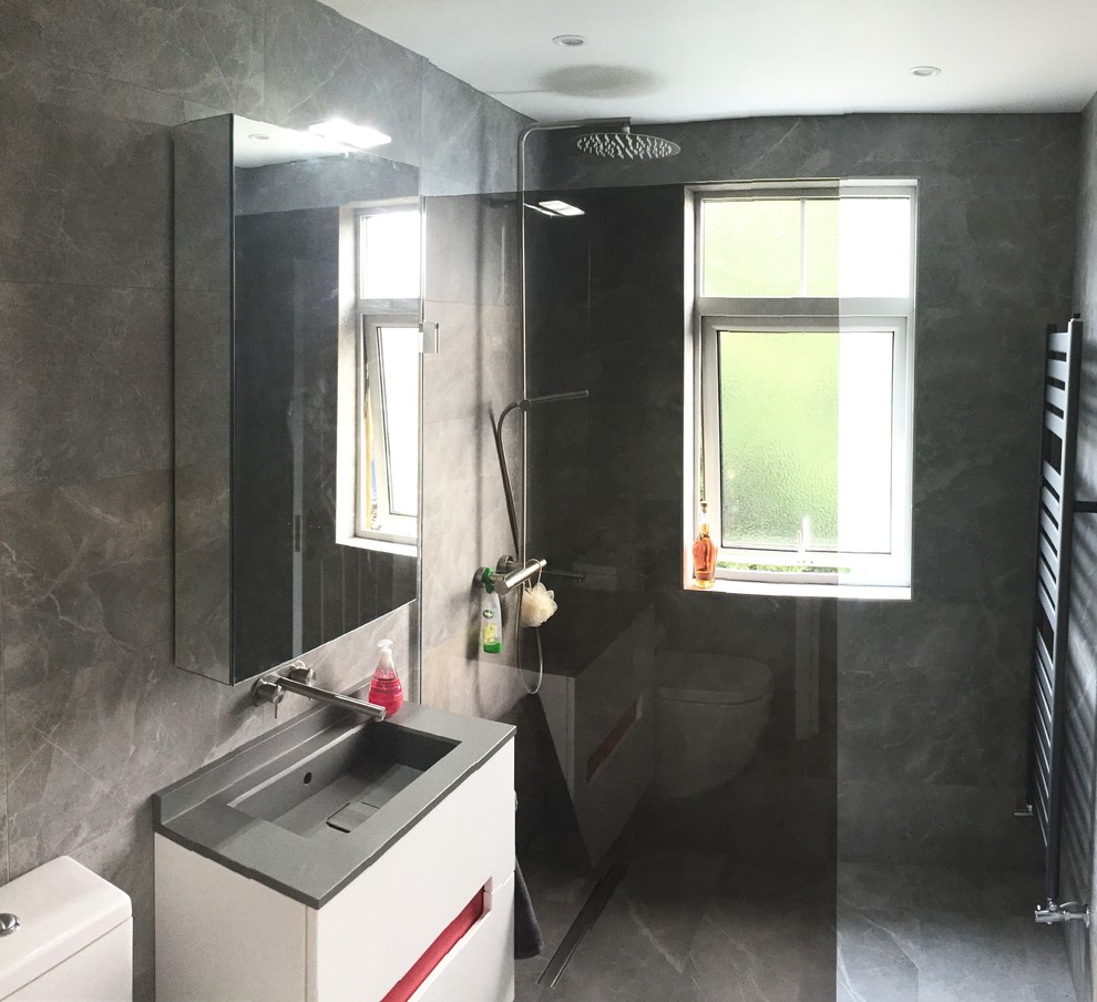 Foto på ett litet funkis badrum med dusch, med ett väggmonterat handfat, luckor med glaspanel, vita skåp, marmorbänkskiva, en öppen dusch, en toalettstol med hel cisternkåpa, grå kakel, porslinskakel, flerfärgade väggar och marmorgolv