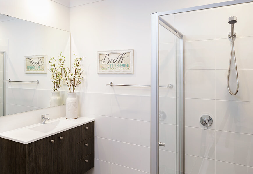 Cette photo montre une salle de bain tendance en bois foncé de taille moyenne avec un placard à porte plane, une douche d'angle, un carrelage blanc, un mur blanc, un lavabo intégré, des carreaux de porcelaine et une cabine de douche à porte battante.