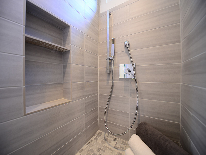 Inspiration för ett stort funkis vit vitt en-suite badrum, med släta luckor, svarta skåp, ett fristående badkar, en dusch i en alkov, beige kakel, brun kakel, grå kakel, stenkakel, grå väggar, klinkergolv i porslin, ett integrerad handfat, bänkskiva i kvarts, grått golv och dusch med gångjärnsdörr