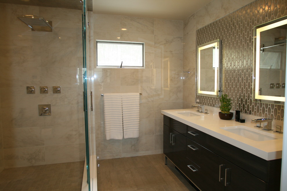 Cette photo montre une salle de bain principale tendance de taille moyenne avec un lavabo encastré, un placard à porte plane, des portes de placard grises, un plan de toilette en quartz modifié, une douche d'angle, WC à poser, un carrelage gris, des carreaux de porcelaine, un sol en carrelage de porcelaine, un mur beige, un sol gris, une cabine de douche à porte coulissante, un bain bouillonnant, un plan de toilette blanc, une niche, meuble double vasque et un plafond voûté.