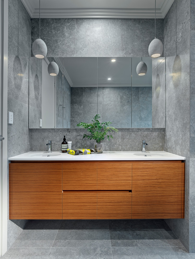Imagen de cuarto de baño principal actual de tamaño medio con puertas de armario de madera oscura, bañera exenta, ducha abierta, paredes grises, lavabo bajoencimera y sanitario de una pieza