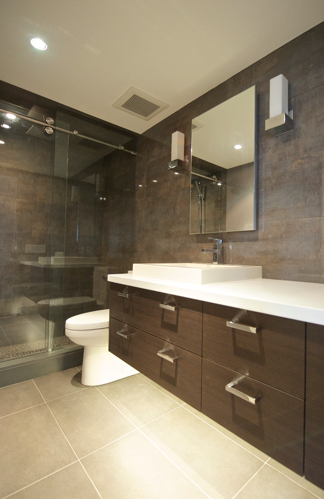 This is an example of a small contemporary bathroom in Toronto with a built-in sink, flat-panel cabinets, dark wood cabinets, engineered stone worktops, an alcove shower, a one-piece toilet, brown tiles, ceramic tiles, brown walls and ceramic flooring.