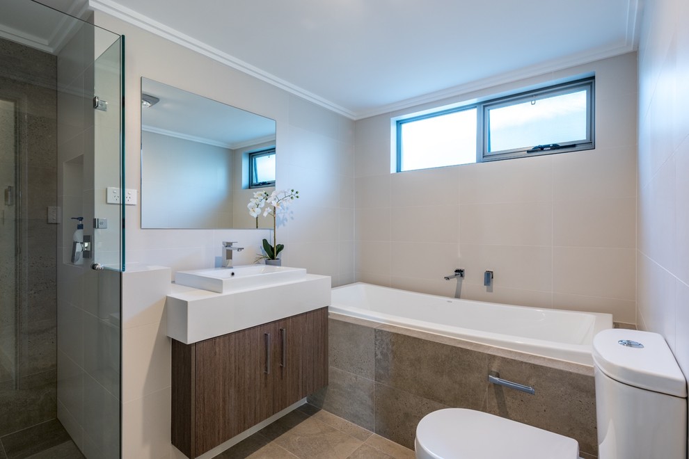 Mid-sized trendy master black and white tile and ceramic tile ceramic tile and gray floor bathroom photo in Perth with flat-panel cabinets, light wood cabinets, a two-piece toilet, beige walls, a drop-in sink, solid surface countertops and a hinged shower door