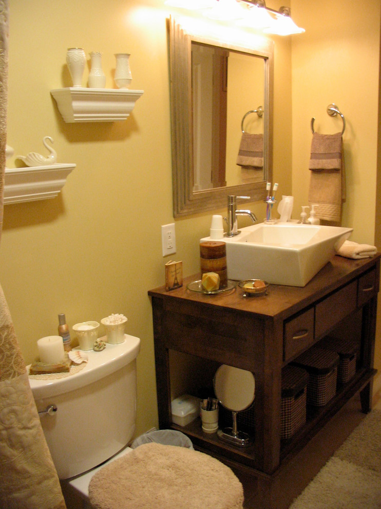 Foto på ett mellanstort vintage badrum med dusch, med släta luckor, skåp i mörkt trä, en toalettstol med hel cisternkåpa, gula väggar, ett fristående handfat, träbänkskiva, ett badkar i en alkov, en dusch/badkar-kombination och klinkergolv i keramik