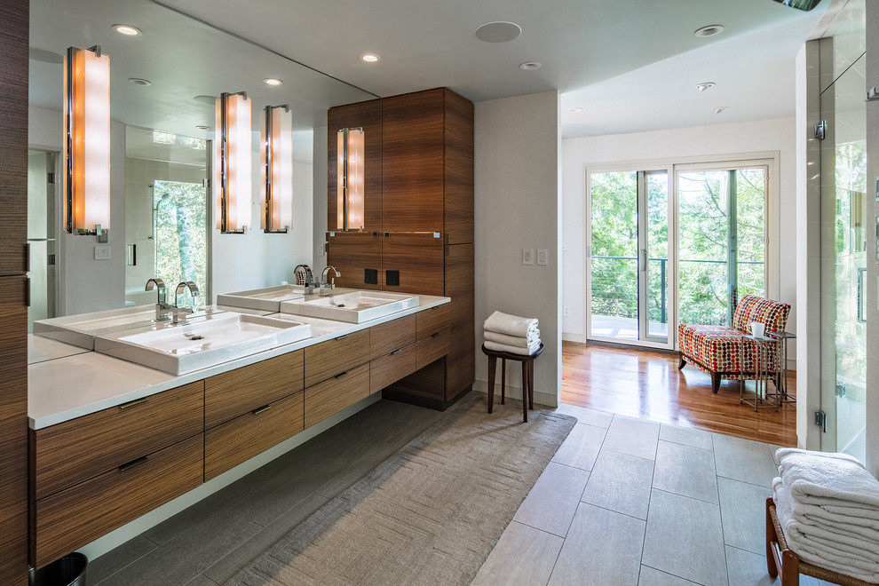 Cette image montre une douche en alcôve design en bois foncé avec un placard à porte plane, un mur gris, une vasque, un sol gris, une cabine de douche à porte battante et un plan de toilette blanc.