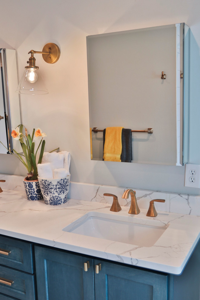Идея дизайна: ванная комната среднего размера в стиле неоклассика (современная классика) с фасадами с утопленной филенкой, синими фасадами, ванной в нише, душем над ванной, белой плиткой, плиткой кабанчик, серыми стенами, полом из керамогранита, душевой кабиной, врезной раковиной, мраморной столешницей, коричневым полом, шторкой для ванной и белой столешницей