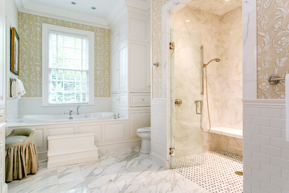This is an example of a large classic ensuite bathroom in Raleigh with raised-panel cabinets, white cabinets, an alcove bath, a built-in shower, a one-piece toilet, white tiles, metro tiles, multi-coloured walls and marble flooring.