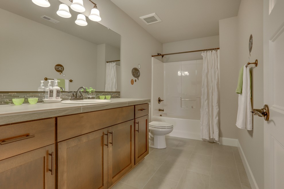Inspiration för ett funkis badrum, med ett nedsänkt handfat, skåp i shakerstil, skåp i mellenmörkt trä, kaklad bänkskiva, en dusch/badkar-kombination, grå kakel, stenkakel, vita väggar och klinkergolv i keramik