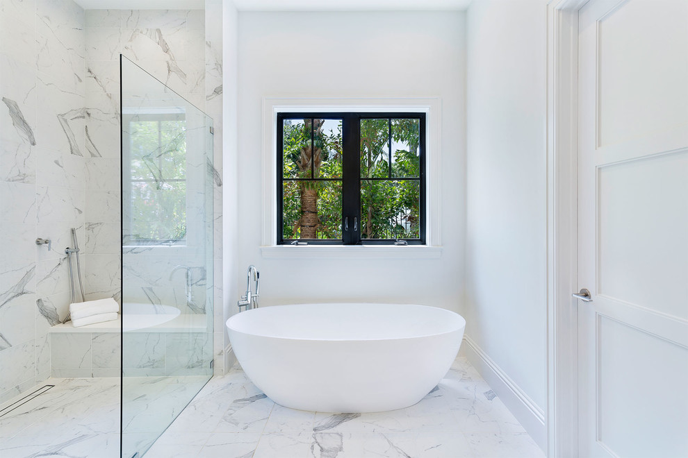 This is an example of a large contemporary ensuite bathroom in Miami with a freestanding bath, white tiles, marble tiles, white walls, marble flooring, white floors, recessed-panel cabinets, white cabinets, a built-in shower, a one-piece toilet, a submerged sink, solid surface worktops, a hinged door and grey worktops.