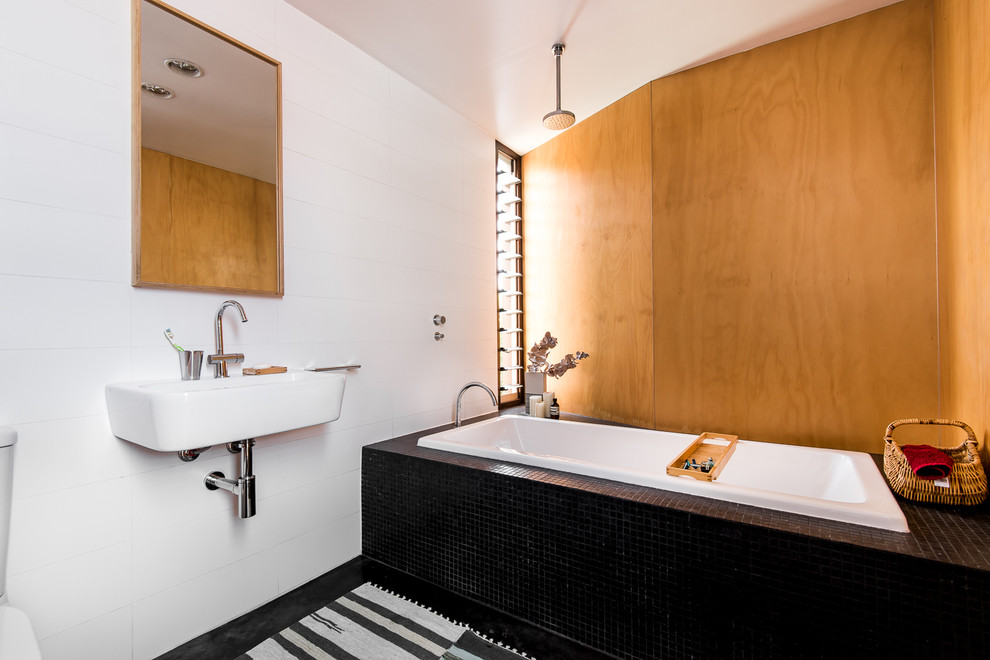 パースにある中くらいな北欧スタイルのおしゃれなマスターバスルーム (ドロップイン型浴槽、シャワー付き浴槽	、白い壁、壁付け型シンク、黒いタイル) の写真