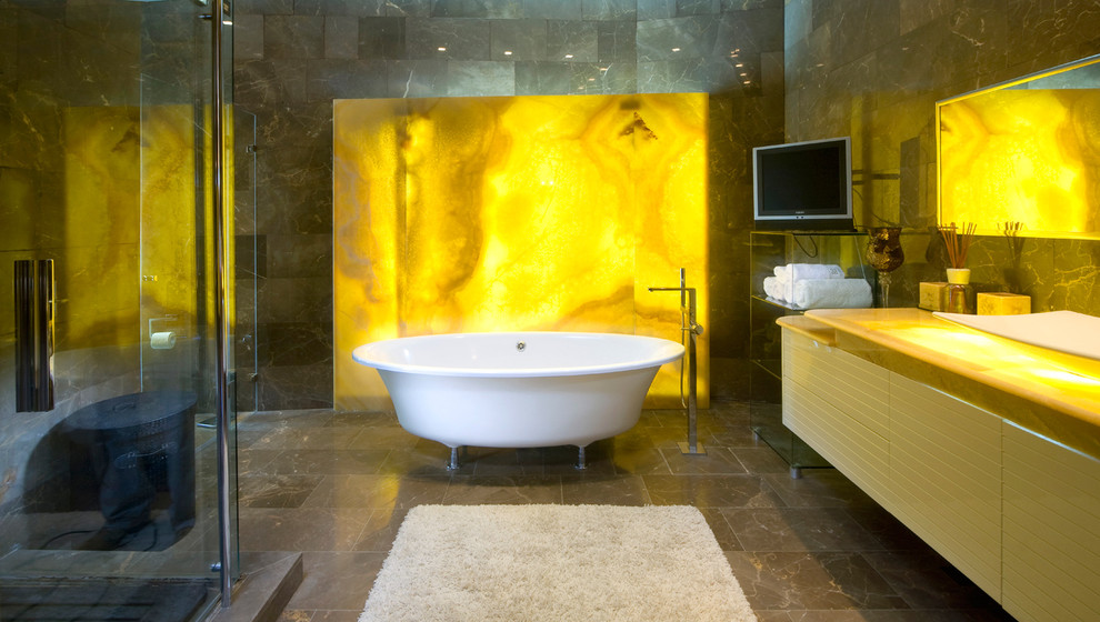Cette image montre une salle de bain design avec une baignoire sur pieds, des dalles de pierre et un plan de toilette en onyx.