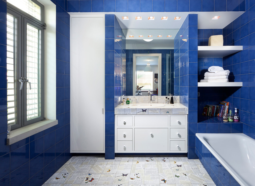 Inspiration för ett funkis badrum, med ett nedsänkt handfat, ett platsbyggt badkar, blå kakel, släta luckor och vita skåp