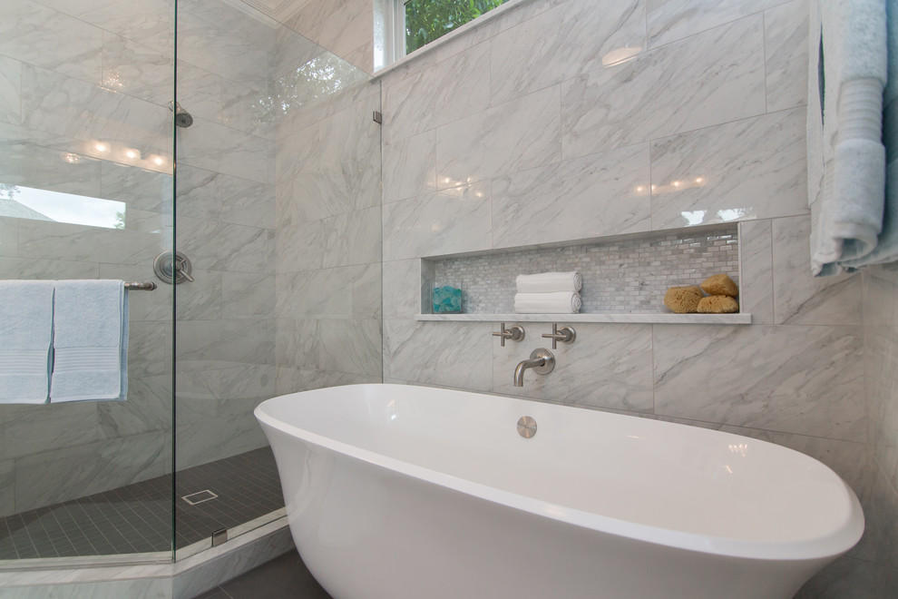 На фото: большая главная ванная комната в классическом стиле с стеклянными фасадами, белыми фасадами, отдельно стоящей ванной, угловым душем, унитазом-моноблоком, белой плиткой, мраморной плиткой, белыми стенами, полом из керамогранита, врезной раковиной, мраморной столешницей, серым полом, душем с распашными дверями и белой столешницей