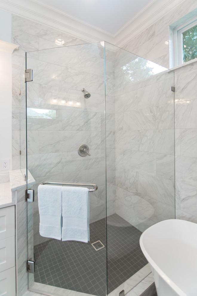 Inspiration for a large traditional ensuite bathroom in Dallas with glass-front cabinets, white cabinets, a freestanding bath, a corner shower, a one-piece toilet, white tiles, marble tiles, white walls, porcelain flooring, a submerged sink, marble worktops, grey floors, a hinged door and white worktops.