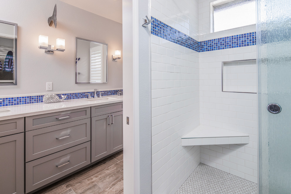 Inspiration for a medium sized nautical ensuite bathroom in San Diego with shaker cabinets, grey cabinets, a corner shower, white tiles, metro tiles, grey walls, porcelain flooring, a submerged sink, engineered stone worktops, brown floors, a sliding door and white worktops.