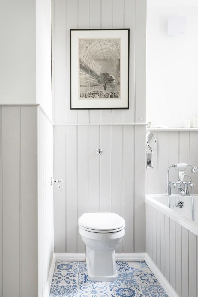 This is an example of a small coastal family bathroom in Sussex with a built-in bath, a one-piece toilet, grey walls, porcelain flooring, a built-in sink, blue floors and a hinged door.