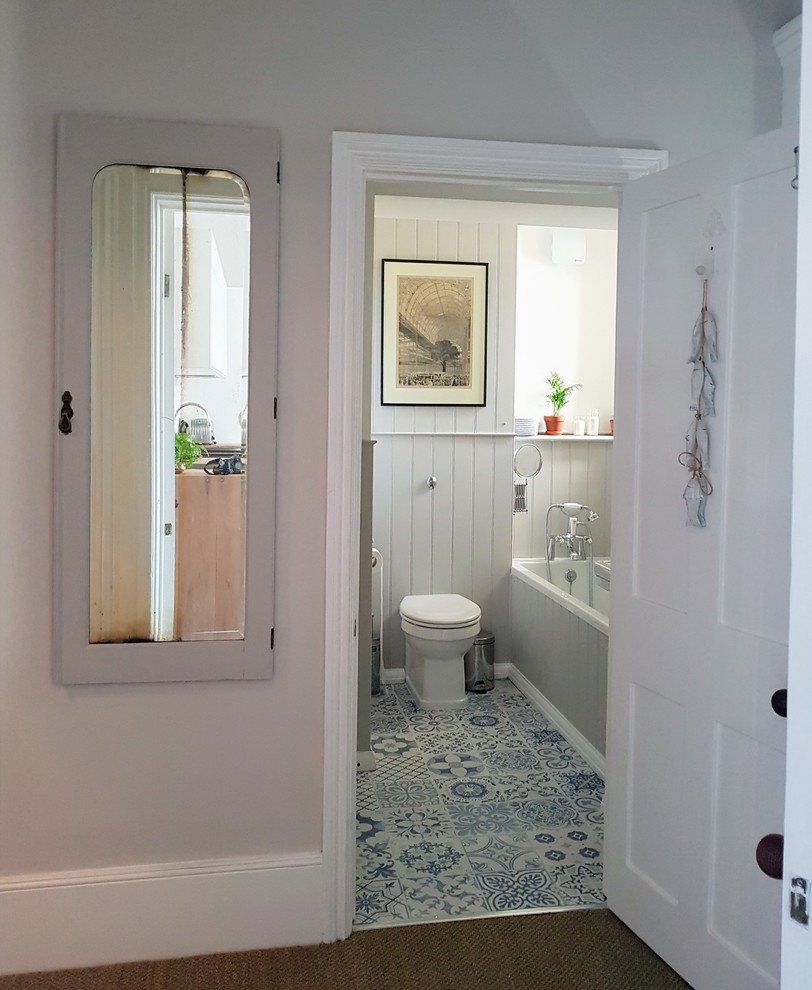 Cette image montre une petite salle de bain marine pour enfant avec une baignoire posée, WC à poser, un mur gris, un sol en carrelage de porcelaine, un lavabo posé, un sol bleu et une cabine de douche à porte battante.