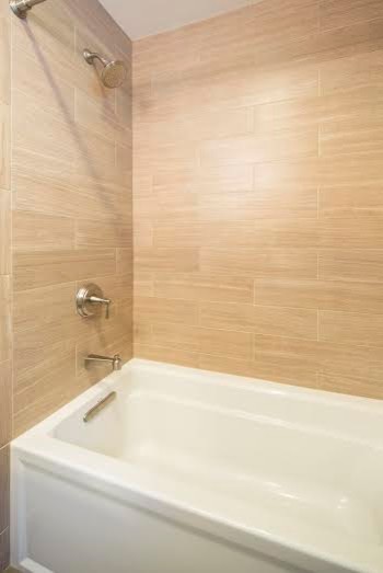 Cette photo montre une salle de bain rétro en bois brun avec une baignoire en alcôve, un carrelage beige, un mur blanc, un lavabo encastré et un plan de toilette en marbre.