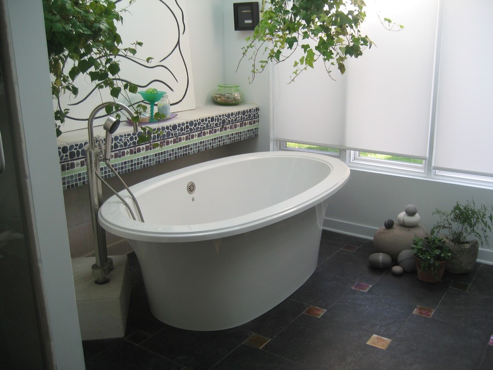This is an example of a bohemian bathroom in Chicago with a freestanding bath, multi-coloured tiles, mosaic tiles, white walls and porcelain flooring.