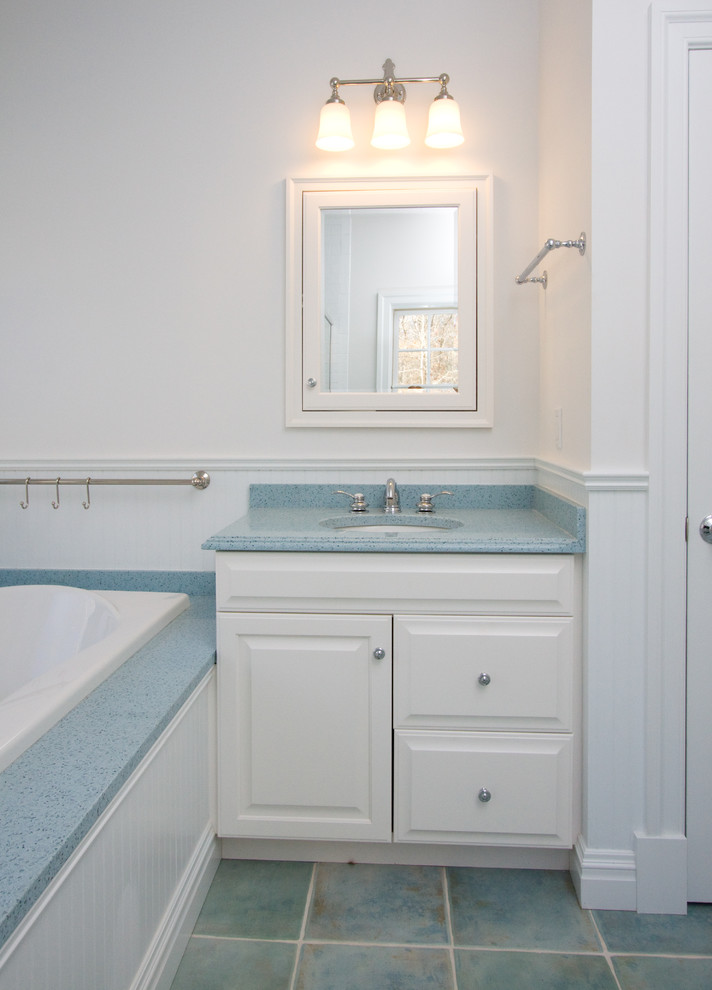 Idées déco pour une salle de bain bord de mer de taille moyenne avec un placard avec porte à panneau surélevé, des portes de placard blanches, une baignoire posée, WC séparés, un carrelage bleu, un mur blanc, un sol en carrelage de céramique, un lavabo encastré, un plan de toilette en quartz modifié et un plan de toilette bleu.