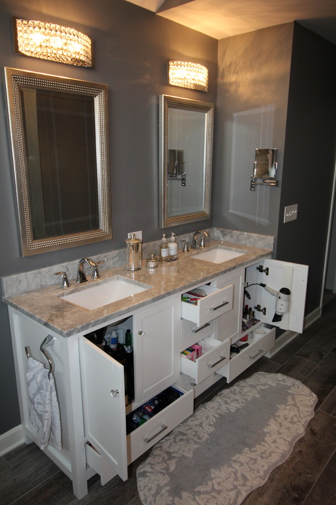 Cette photo montre une salle de bain principale chic de taille moyenne avec un placard avec porte à panneau encastré, des portes de placard blanches, une baignoire indépendante, une douche d'angle, WC à poser, un mur gris et un lavabo encastré.
