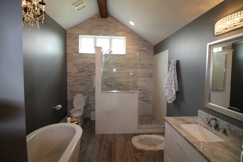 Inspiration pour une salle de bain principale traditionnelle de taille moyenne avec un placard avec porte à panneau encastré, des portes de placard blanches, une baignoire indépendante, une douche d'angle, WC à poser, un mur gris et un lavabo encastré.