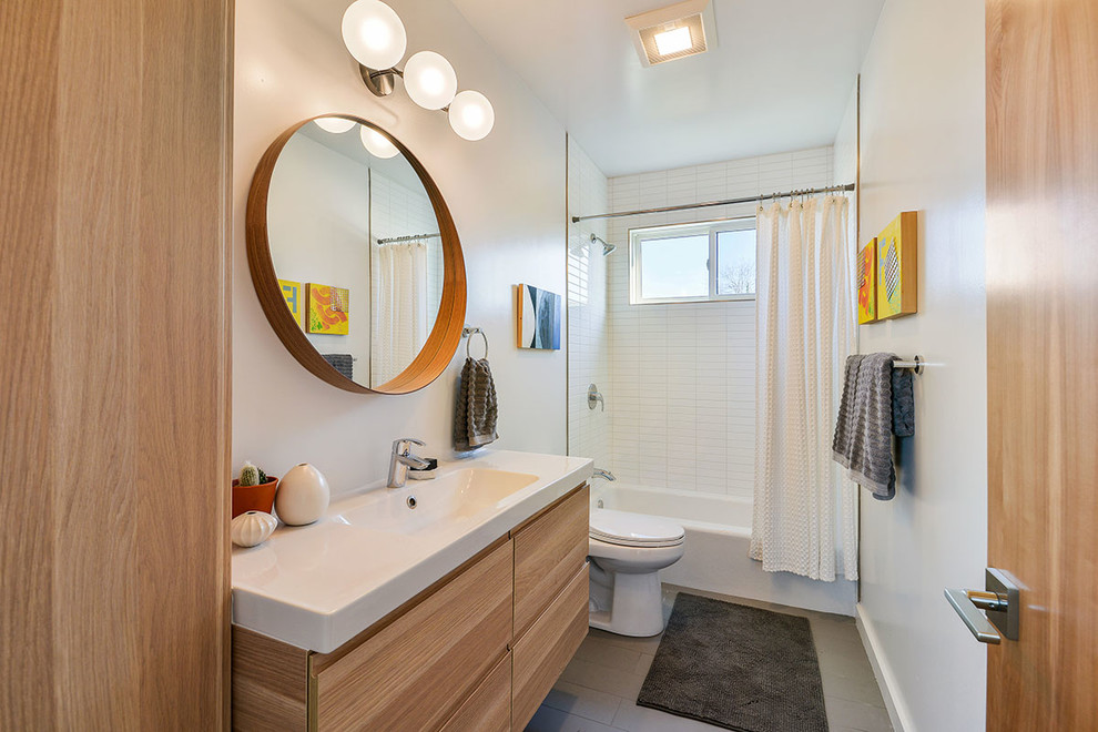 This is an example of a medium sized contemporary shower room bathroom in San Francisco with flat-panel cabinets, light wood cabinets, an alcove bath, a shower/bath combination, ceramic tiles, white walls, porcelain flooring, quartz worktops, white tiles, a built-in sink and a shower curtain.