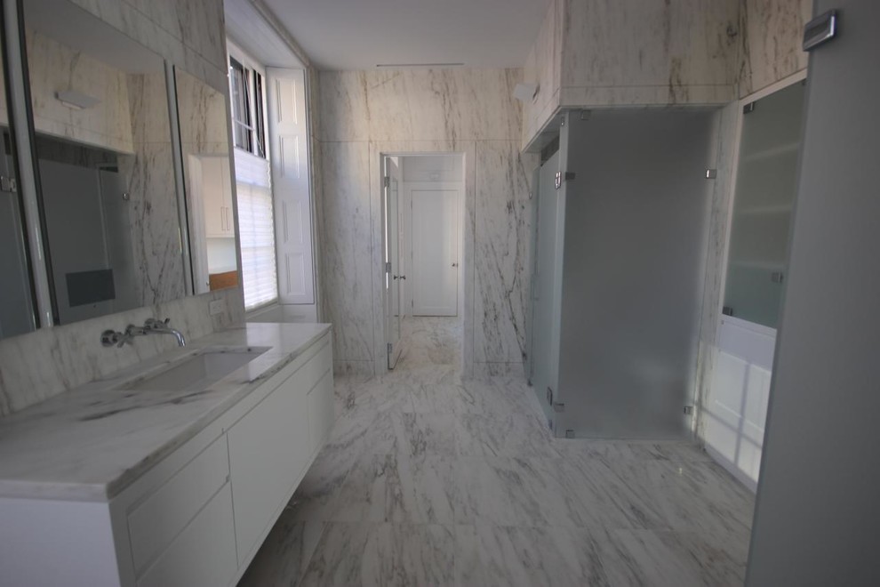 Modern inredning av ett mellanstort en-suite badrum, med ett undermonterad handfat, släta luckor, vita skåp, träbänkskiva, ett badkar i en alkov, en hörndusch, en toalettstol med separat cisternkåpa, vit kakel, stenkakel, vita väggar och linoleumgolv