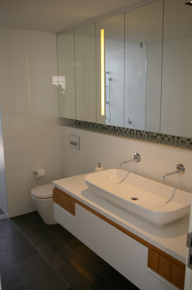 Ejemplo de cuarto de baño actual con lavabo de seno grande, paredes blancas, armarios tipo vitrina, baldosas y/o azulejos blancos y ducha a ras de suelo
