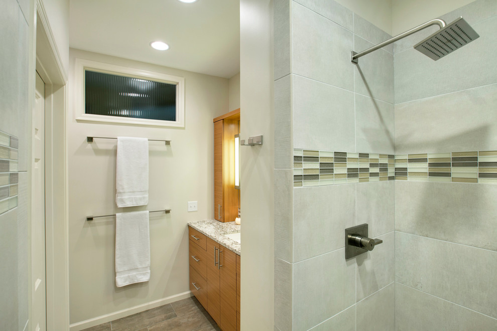 Design ideas for a large contemporary ensuite bathroom in Minneapolis with flat-panel cabinets, light wood cabinets, a walk-in shower, a two-piece toilet, grey tiles, porcelain tiles, beige walls, porcelain flooring, a submerged sink and granite worktops.