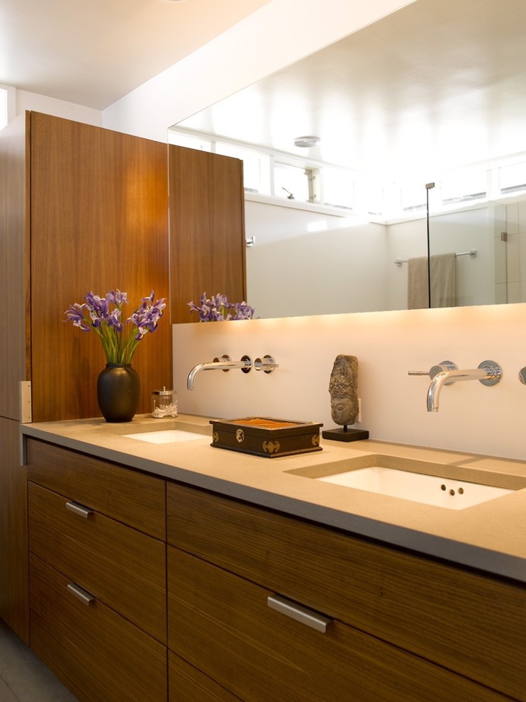 Aménagement d'une salle de bain contemporaine avec un plan de toilette en surface solide et un lavabo encastré.