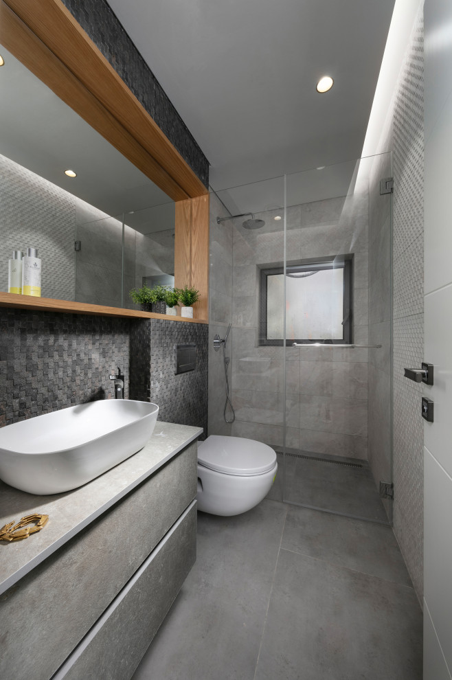 Inspiration for a contemporary kids' gray tile gray floor alcove shower remodel with flat-panel cabinets, gray cabinets, a vessel sink, a hinged shower door and gray countertops