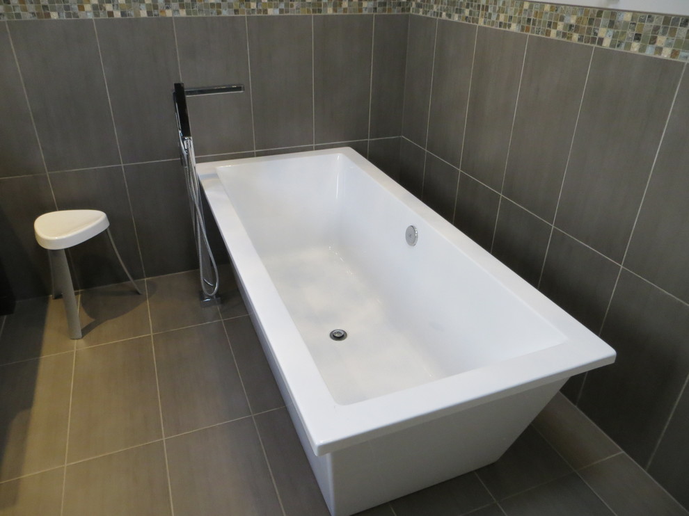 Photo of a large contemporary ensuite bathroom in Other with dark wood cabinets, a freestanding bath, a corner shower, a one-piece toilet, multi-coloured tiles, ceramic tiles, grey walls, granite worktops, grey floors, a hinged door and recessed-panel cabinets.