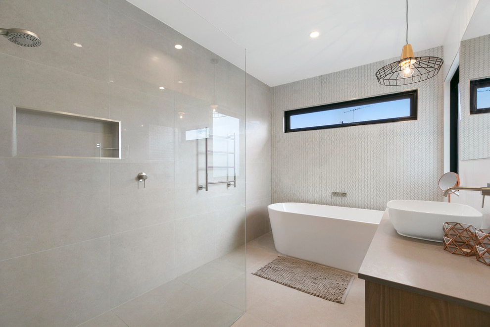 Bild på ett mellanstort funkis grå grått badrum, med skåp i ljust trä, ett fristående badkar, en öppen dusch, grå kakel, stenkakel, grå väggar, klinkergolv i porslin, bänkskiva i kvarts, grått golv och med dusch som är öppen