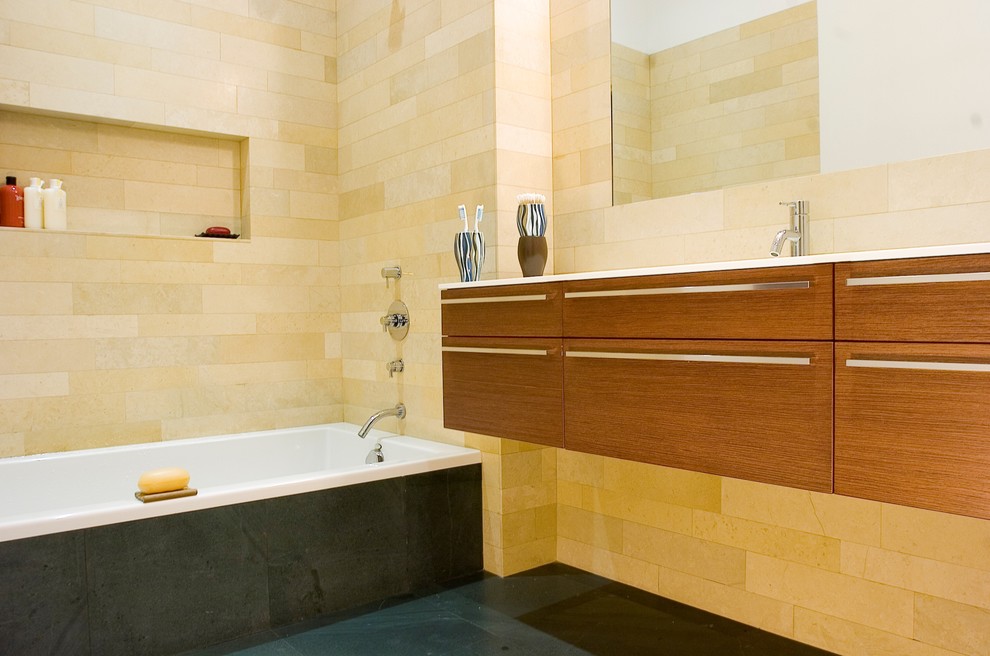 Diseño de cuarto de baño minimalista con armarios con paneles lisos, puertas de armario de madera oscura, bañera empotrada, baldosas y/o azulejos beige y baldosas y/o azulejos de piedra